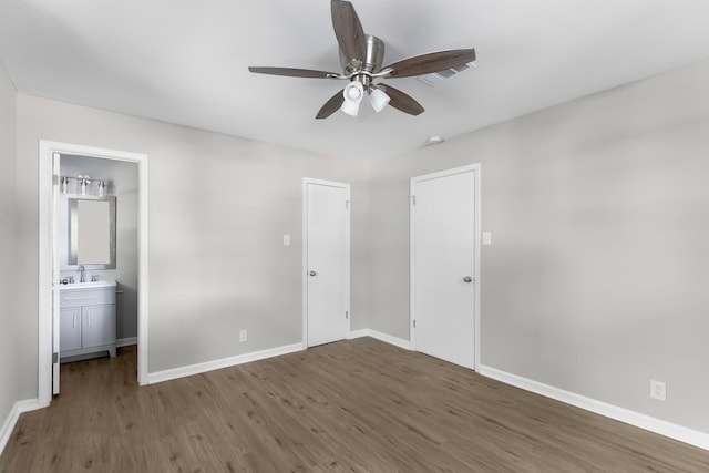 unfurnished bedroom featuring ensuite bath, ceiling fan, dark wood-type flooring, and sink