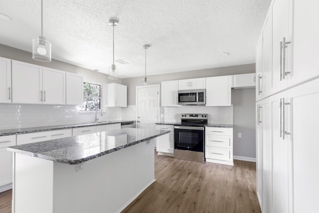 kitchen featuring a center island, white cabinetry, stainless steel appliances, and hanging light fixtures