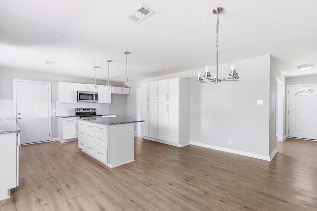 kitchen featuring appliances with stainless steel finishes, light wood-type flooring, white cabinetry, and hanging light fixtures