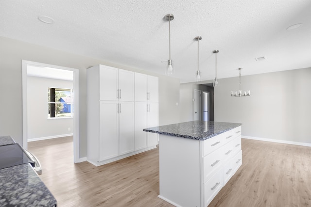 kitchen featuring white cabinets, a center island, light hardwood / wood-style floors, and hanging light fixtures