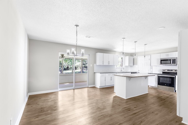 kitchen with white cabinetry, a center island, stainless steel appliances, tasteful backsplash, and pendant lighting