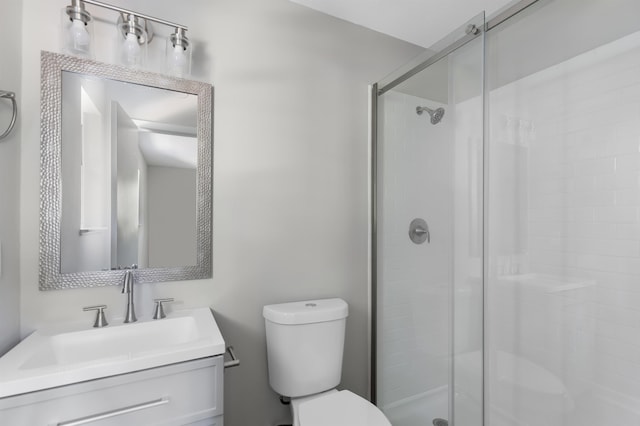 bathroom featuring a shower with door, vanity, and toilet