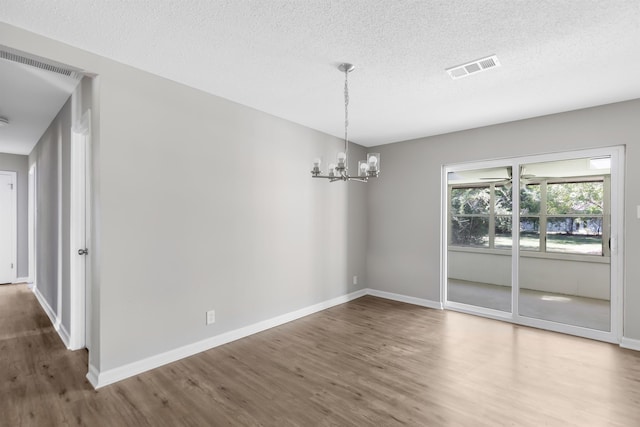 unfurnished dining area featuring a chandelier, hardwood / wood-style floors, and a textured ceiling