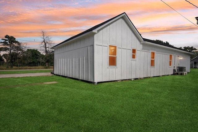 property exterior at dusk with a lawn and central AC