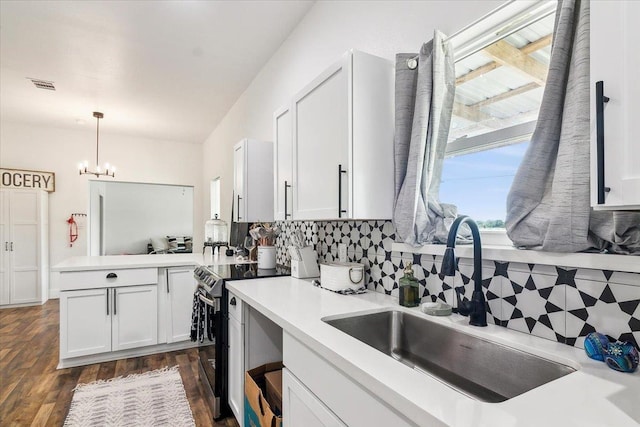 kitchen featuring tasteful backsplash, sink, white cabinets, hanging light fixtures, and stainless steel range with electric cooktop