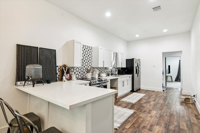 kitchen with white cabinets, a kitchen breakfast bar, sink, appliances with stainless steel finishes, and kitchen peninsula