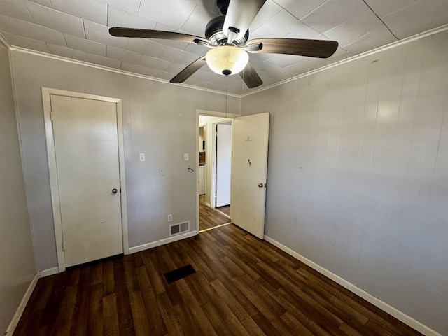 unfurnished bedroom featuring dark wood-type flooring, ceiling fan, and crown molding