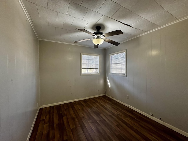 empty room with crown molding, dark wood-type flooring, and ceiling fan