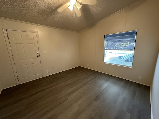 empty room with a textured ceiling, vaulted ceiling, ceiling fan, and dark wood-type flooring