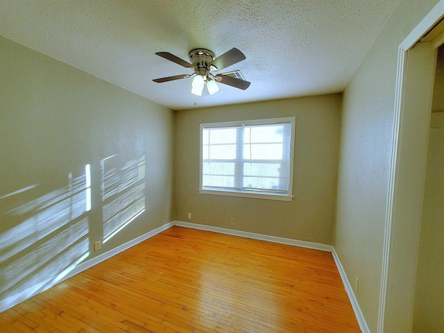 spare room with a textured ceiling, light wood-type flooring, and ceiling fan