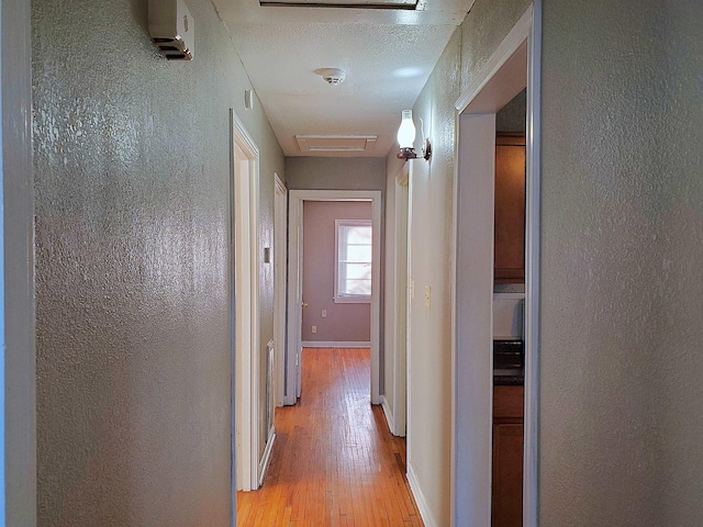 corridor with a textured ceiling and light wood-type flooring