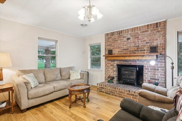 living room featuring a wood stove, ornamental molding, wood-type flooring, and a notable chandelier