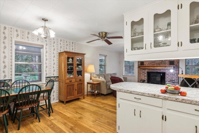 kitchen with decorative light fixtures, white cabinetry, a wood stove, and light hardwood / wood-style flooring