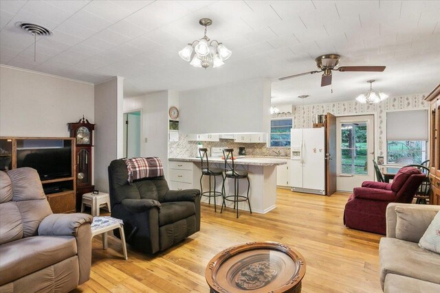 living room featuring light hardwood / wood-style flooring, ceiling fan with notable chandelier, and sink