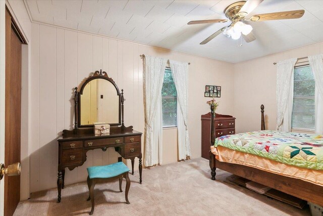 carpeted bedroom featuring ceiling fan, wood walls, and a closet