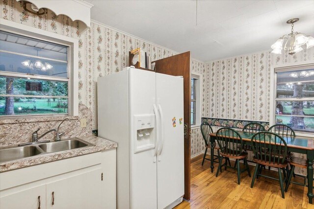 kitchen featuring light wood-type flooring, decorative light fixtures, a notable chandelier, white cabinetry, and white fridge with ice dispenser