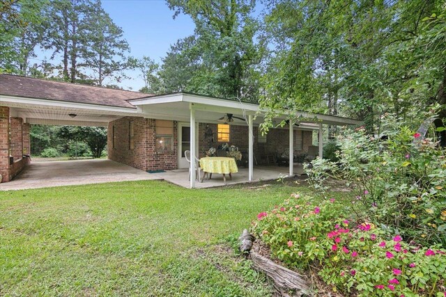 rear view of house featuring a lawn, ceiling fan, and a carport