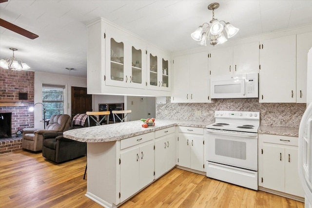 kitchen with kitchen peninsula, white appliances, decorative light fixtures, and white cabinets