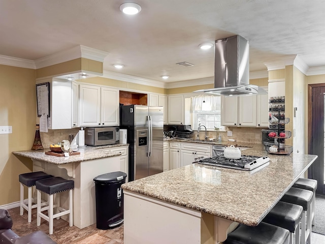 1100 Mitzi Rd, Vidor, TX 77662 - kitchen featuring island range hood, stainless steel appliances, a peninsula, a sink, and a breakfast bar