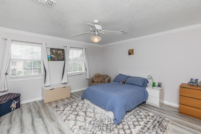 bedroom featuring baseboards, visible vents, ornamental molding, and wood finished floors