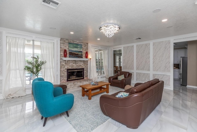 living room with a textured ceiling, visible vents, a brick fireplace, an inviting chandelier, and recessed lighting