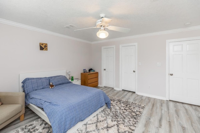 bedroom featuring visible vents, ornamental molding, baseboards, and wood finished floors