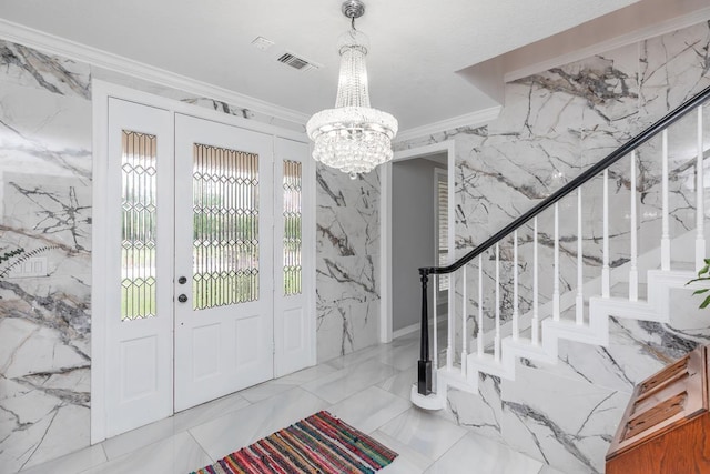 entryway with crown molding, stone wall, marble finish floor, a notable chandelier, and stairs