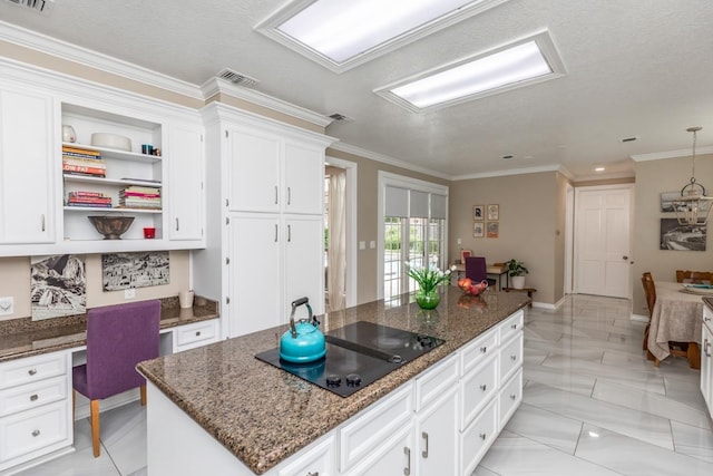 kitchen with visible vents, a center island, built in desk, white cabinets, and black electric stovetop