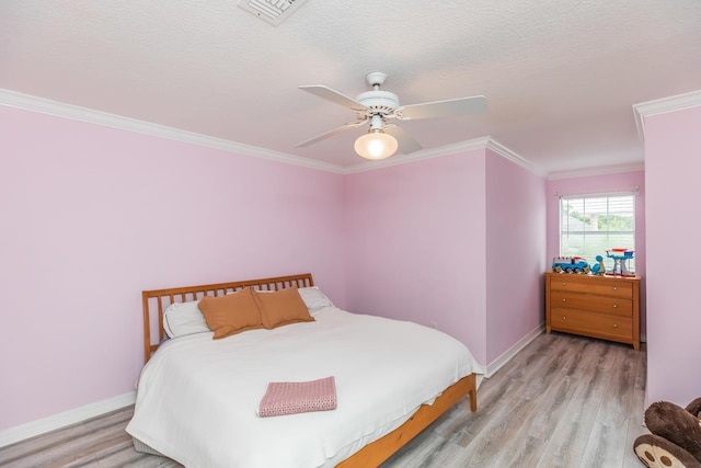 bedroom with baseboards, ornamental molding, light wood finished floors, and visible vents