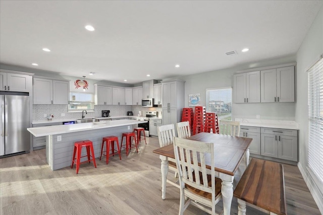 1326 Emerald Dr, Port Bolivar, TX 77650 - kitchen with stainless steel appliances, gray cabinetry, a breakfast bar, light countertops, and healthy amount of natural light