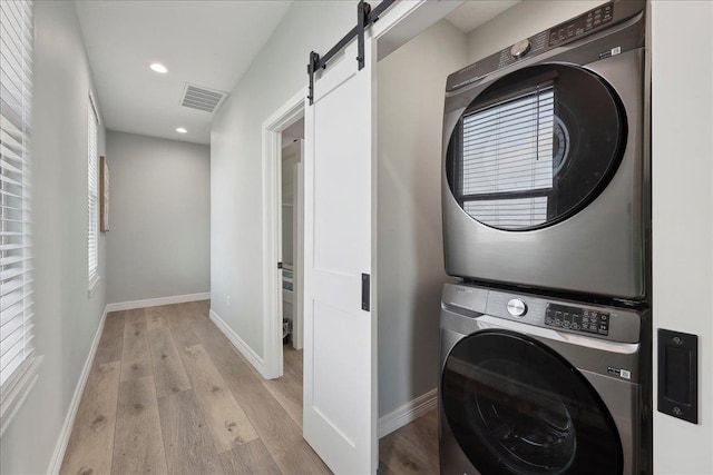 1326 Emerald Dr, Port Bolivar, TX 77650 - washroom with estacked washer and dryer, a barn door, light wood-type flooring, and recessed lighting