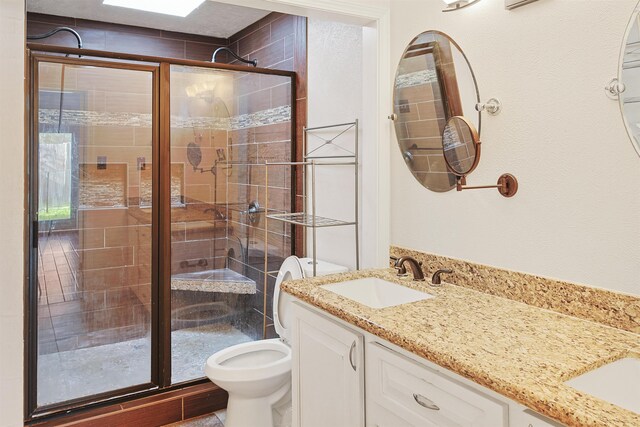 bathroom with vanity, toilet, and a shower with door