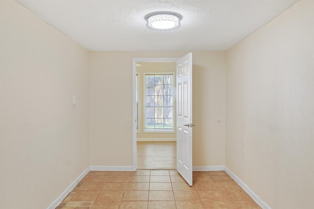 empty room featuring a textured ceiling and light tile patterned flooring