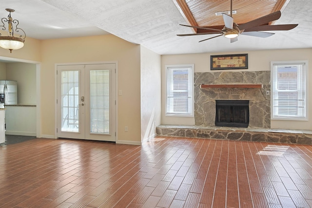 unfurnished living room featuring ceiling fan, a fireplace, a healthy amount of sunlight, and french doors