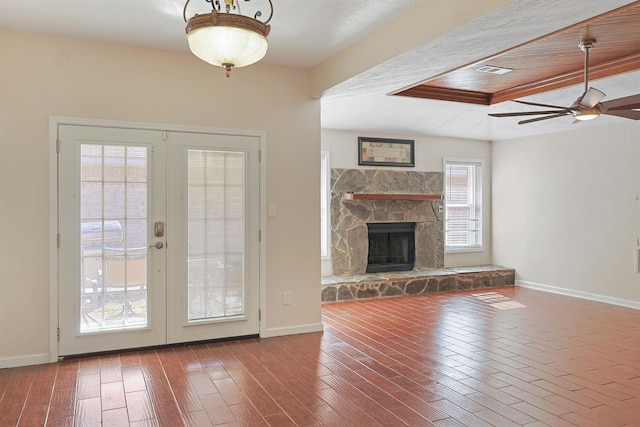 unfurnished living room with french doors, a stone fireplace, and ceiling fan