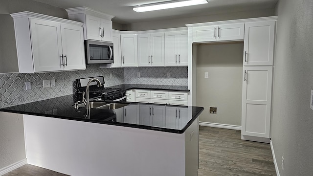 kitchen featuring kitchen peninsula, appliances with stainless steel finishes, tasteful backsplash, sink, and white cabinets