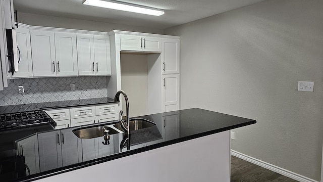 kitchen with white cabinets, gas stovetop, and backsplash