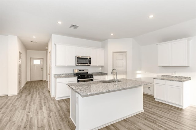 kitchen featuring white cabinets, sink, stainless steel appliances, and an island with sink