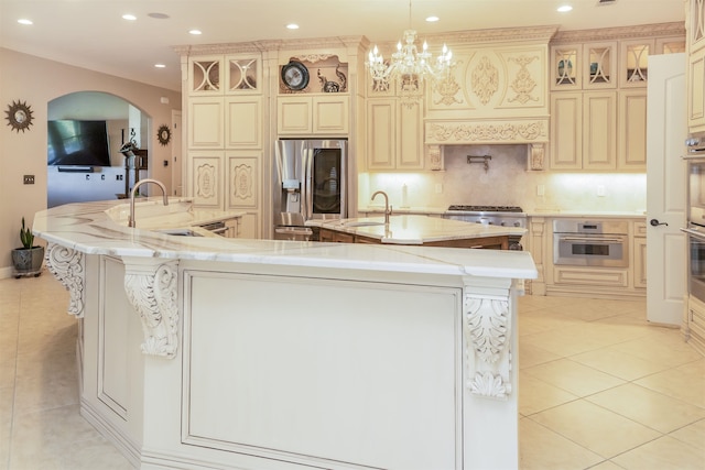 10940 Sheila Ct, Beaumont, TX 77705 - kitchen featuring appliances with stainless steel finishes, a large island with sink, light tile patterned floors, recessed lighting, and arched walkways