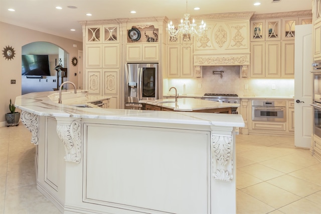 kitchen with a sink, a spacious island, appliances with stainless steel finishes, and light tile patterned floors