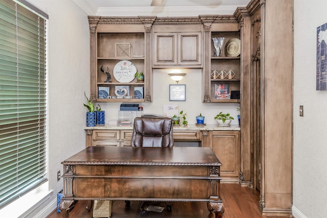 home office with dark wood-type flooring, crown molding, built in desk, and baseboards