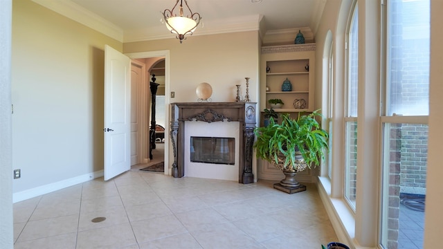 living area featuring baseboards, built in features, ornamental molding, light tile patterned floors, and a glass covered fireplace