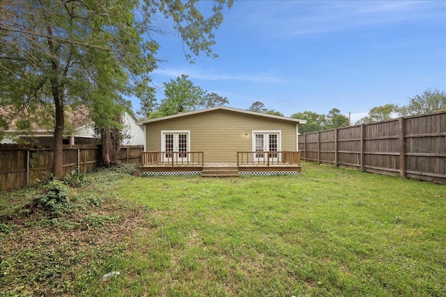 back of property featuring a lawn, a deck, french doors, and a fenced backyard