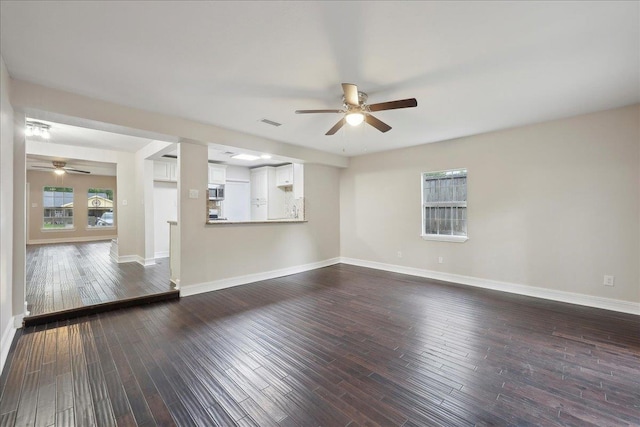 unfurnished living room featuring dark wood-style flooring, ceiling fan, and baseboards