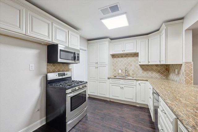 kitchen featuring visible vents, light stone counters, a sink, dark wood finished floors, and appliances with stainless steel finishes