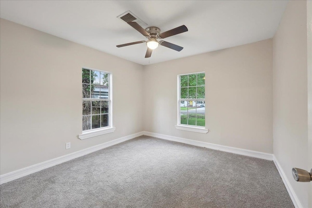 carpeted empty room featuring baseboards, a ceiling fan, and visible vents