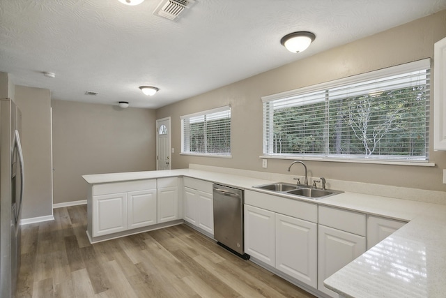 kitchen with white cabinets, stainless steel appliances, kitchen peninsula, and sink