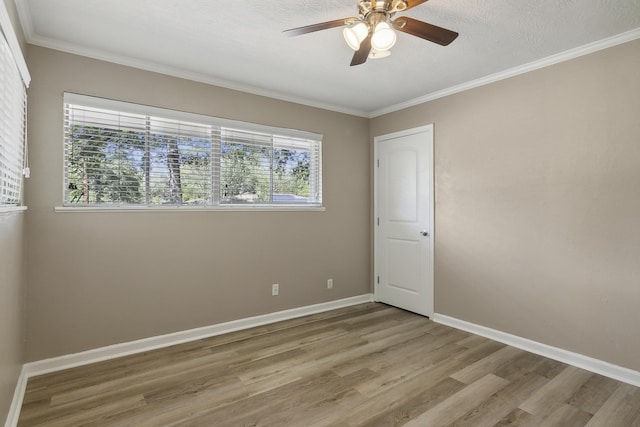 empty room with a textured ceiling, ceiling fan, wood-type flooring, and crown molding