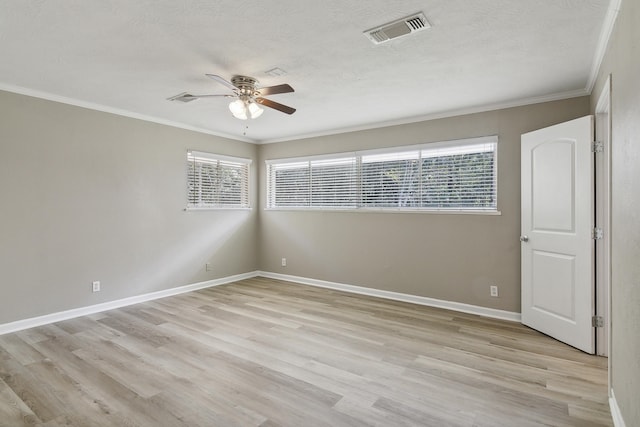 spare room with crown molding, plenty of natural light, and light hardwood / wood-style floors