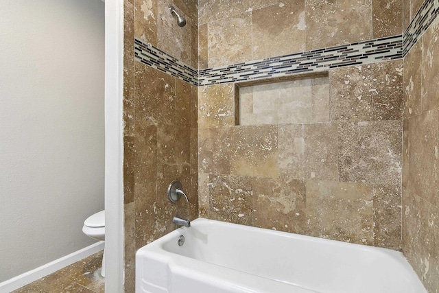 bathroom with toilet and tiled shower / bath